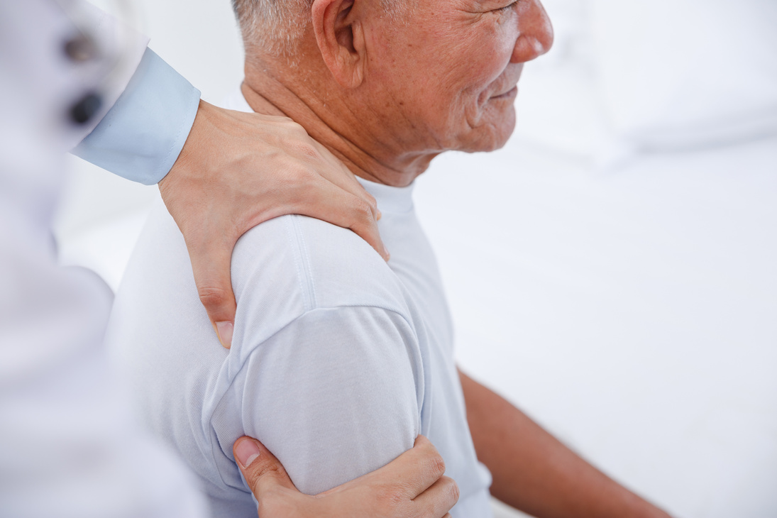 Doctor physiotherapist doing healing treatment to old man.